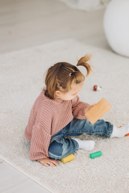 The girl learns colors by playing with wooden cylindrical toy colored human figures and placing them in cups of the appropriate color The child is happy that he completed the task correctly