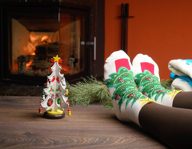 Girl legs in socks near the fireplace with a little christmas tree Winter holiday concept Cozy relaxed magical atmosphere