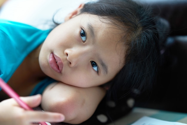 Girl lie down for writing notebook on floor