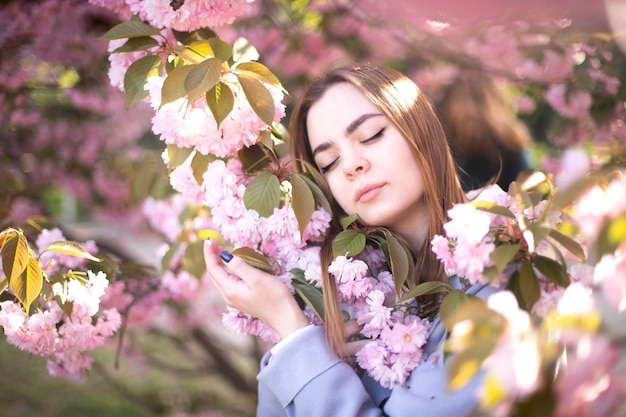 The girl lies on sakura flowers. A beautiful girl sleeps in a flower garden