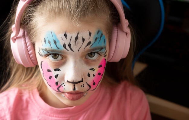 girl listen music in pink headphones aquagrim on face