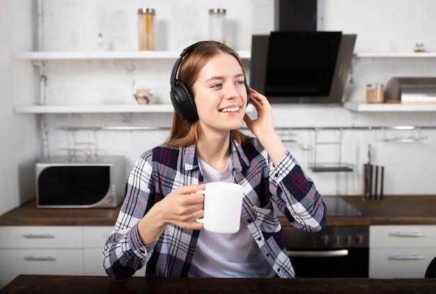 The girl listens to music on headphones and drinks coffee