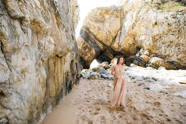 Girl in long dress near rocks and ocean