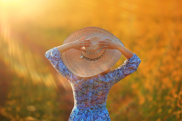 Girl in a long vintage dress hat in a field of flowers, happy summer sunny freedom female