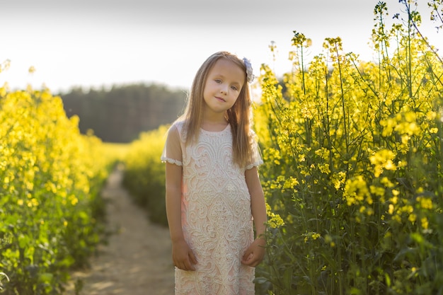 girl in a long white dress in a rapeseed field in summer