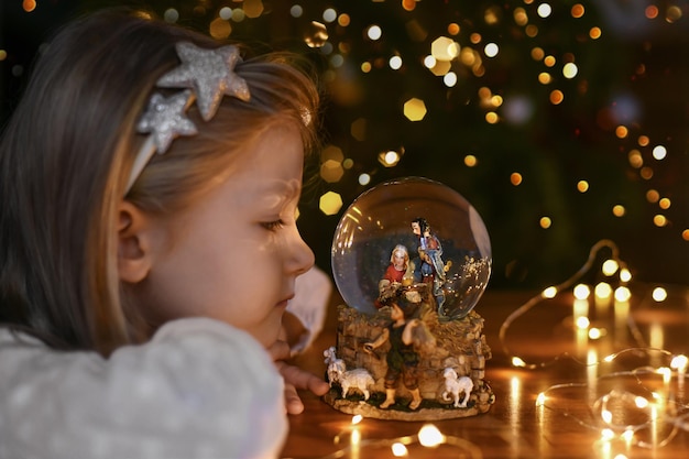 Girl looking at a glass ball with a scene of the birth of jesus christ