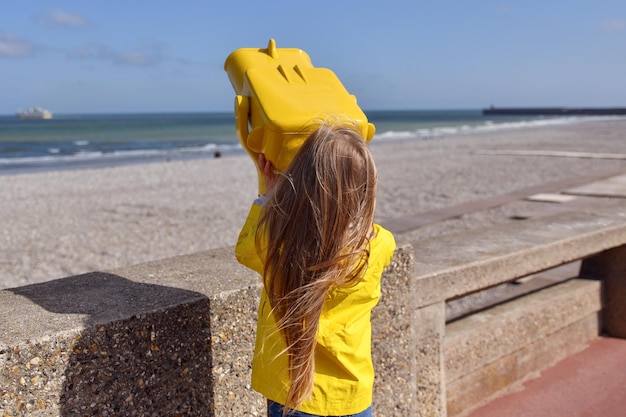 A girl looking at the ocean through a binoscope