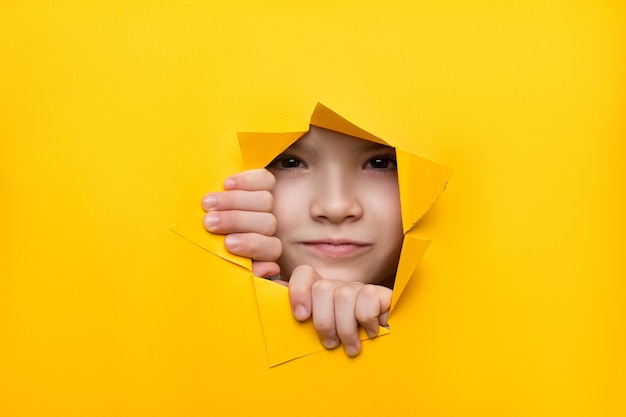 Girl looking through a hole in colored paper