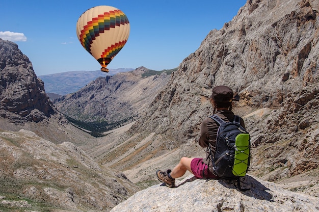 A girl looks at a bright hot air balloon in a beautiful valley of Turkey