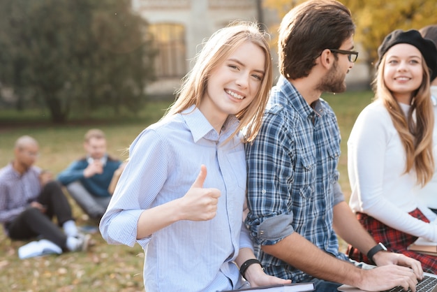 The girl looks into the camera, sitting with friends.