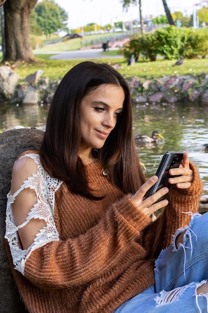 Girl looks at phone on bank of river