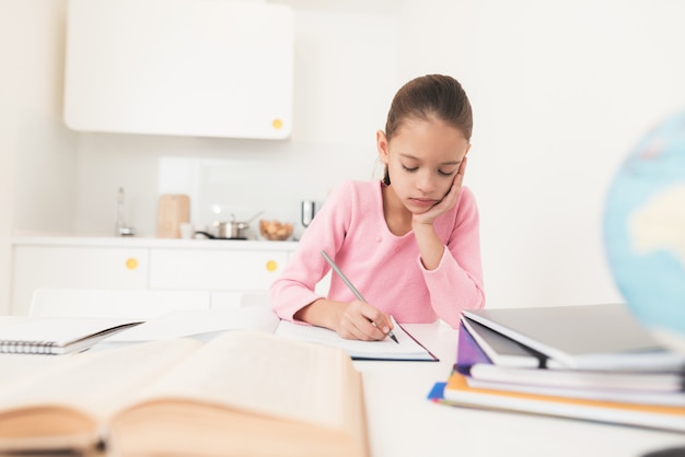 Girl looks thoughtfully into the textbook.