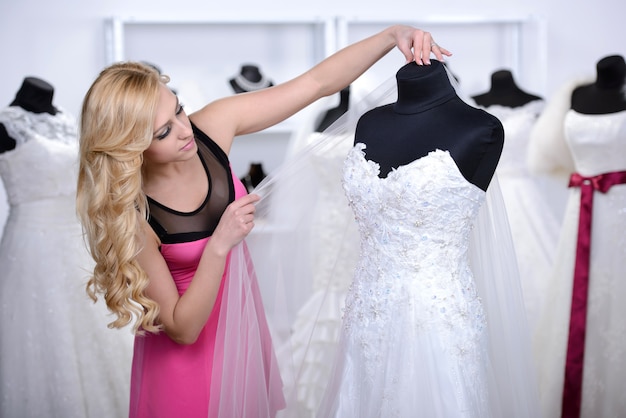 The girl looks at the wedding white dress in the store.