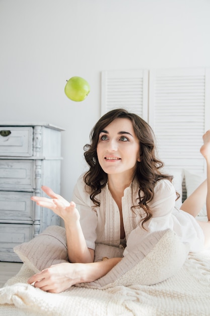 Girl lying on the bed in the morning and throws the Apple up