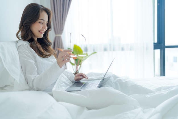 Girl lying in bed playing laptop in bedroom