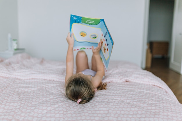 Girl lying on bed and reading book