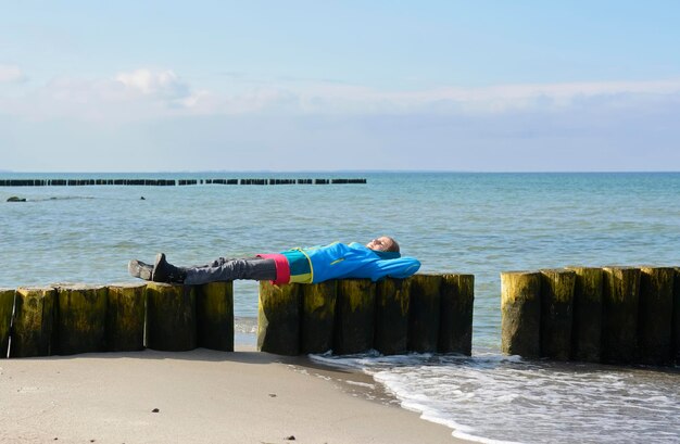 Photo girl lying on groynes at beach against sky