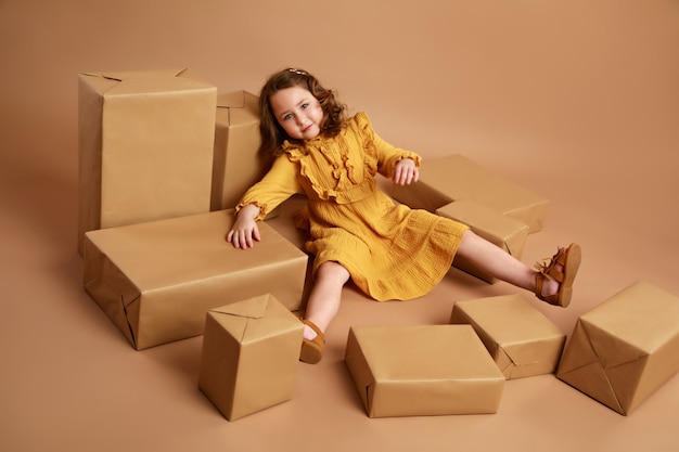 Girl lying in the middle of scattered boxes with gifts as doll