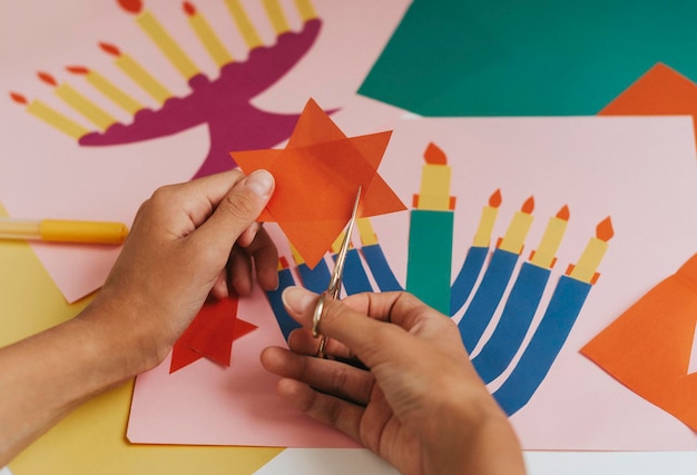 A girl makes a card for happy Hanukkah with her hands a candelabra and candles on the card