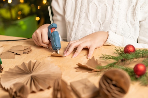 Photo girl makes christmas tree decorations out of paper with her own hands step 3