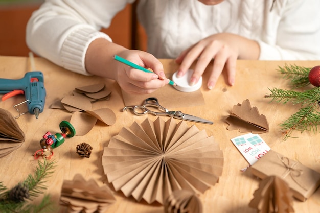 girl makes Christmas tree decorations out of paper with her own hands