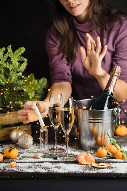 Girl makes a christmas wish and puts it in little glass bottle and cross fingers champagne in metal ...