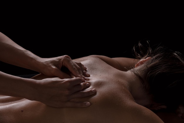 A girl makes a massage with oil closeup on a dark background