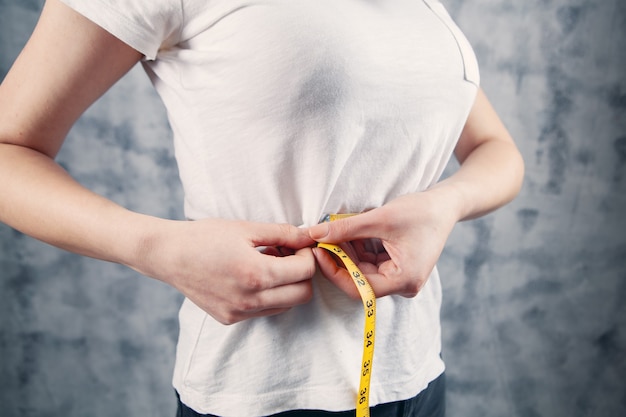 Girl measures belly with a centimeter