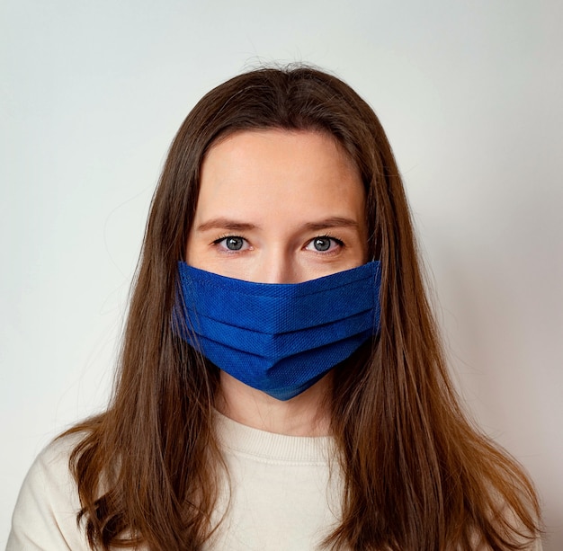 The girl in the medical mask. A woman in a blue medical mask on a light background.