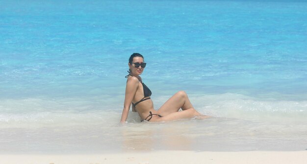 girl model in a black bikini swims in the ocean