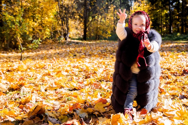 Girl in mom's waistcoat in autumn park