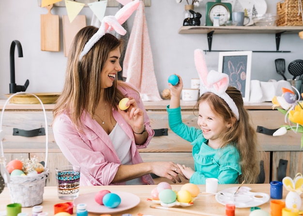 Girl and mother in bunny ears having fun with Easter eggs