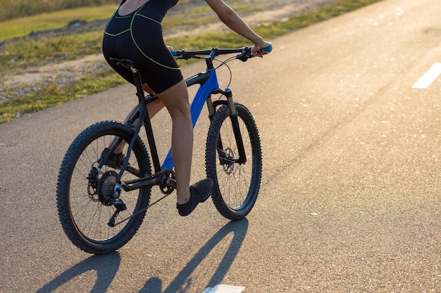 Girl on a mountain bike on offroad beautiful portrait of a cyclist at sunset Fitness girl rides a modern carbon fiber mountain bike in sportswear