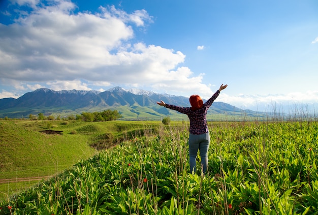 Girl on the nature with joy looks at the mountains.