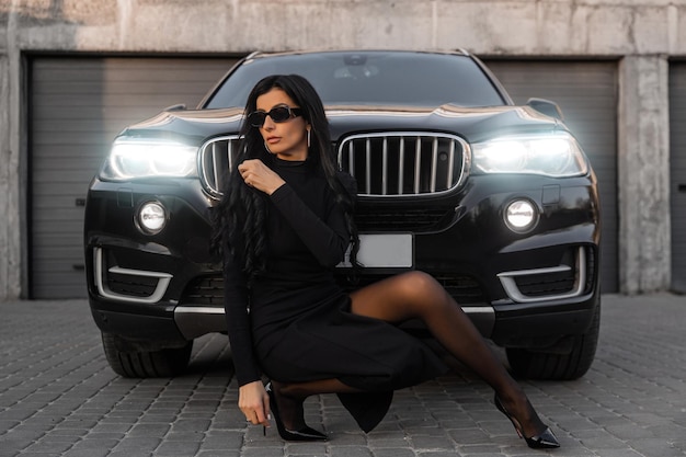 A girl near the car in a black dress