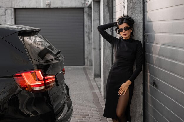 A girl near the car in a black dress