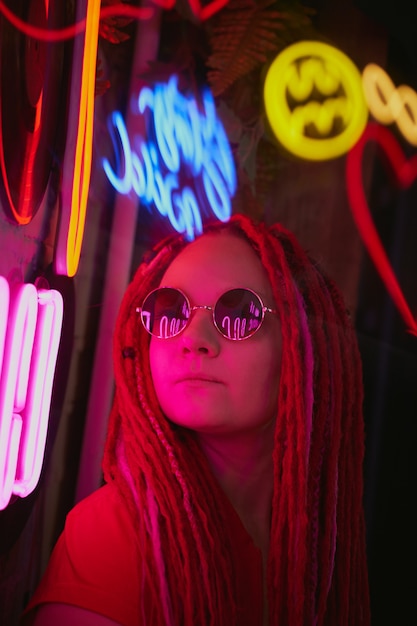 Girl in neon lights, beautiful woman in sunglasses, with pink hair, with dreadlocks pigtails