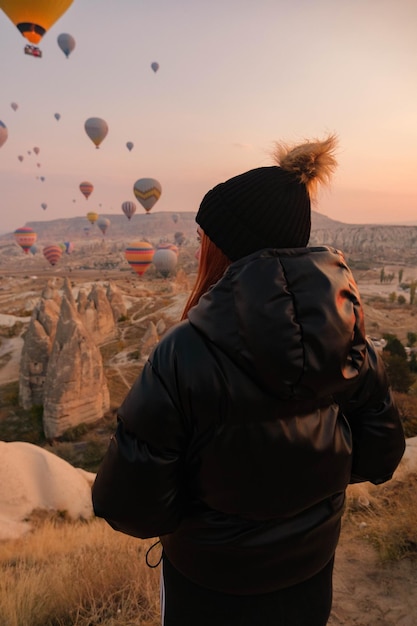 Girl observing the horizon with background of hot air balloons