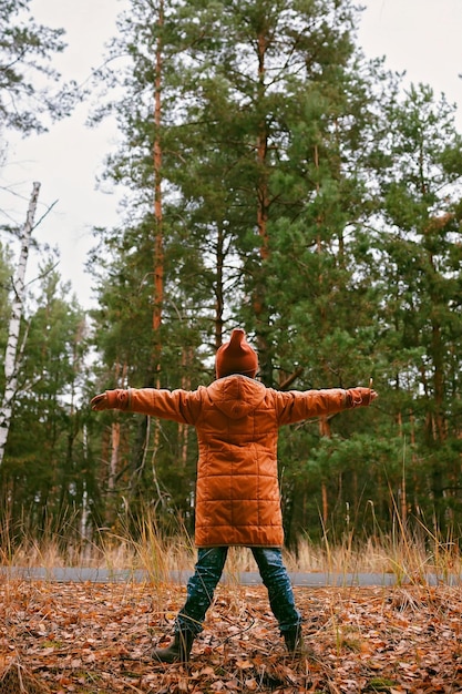 Girl in orange coat with outstretched arms enjoys fresh air in fall forest mental health autumn