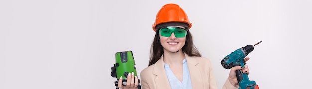 A girl in an orange helmet and a laser level in her hands on a white background