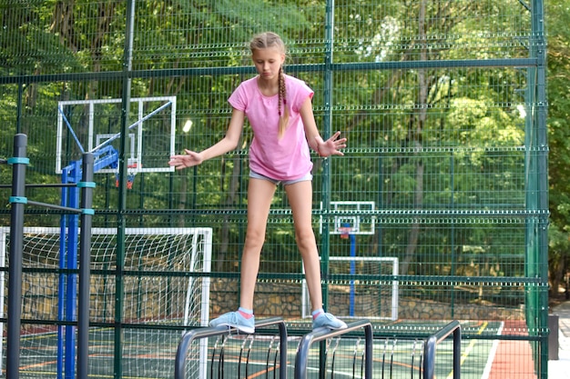 Girl on outdoor sports field. Teenager girl doing gymnastic exercises at outdoor gym.