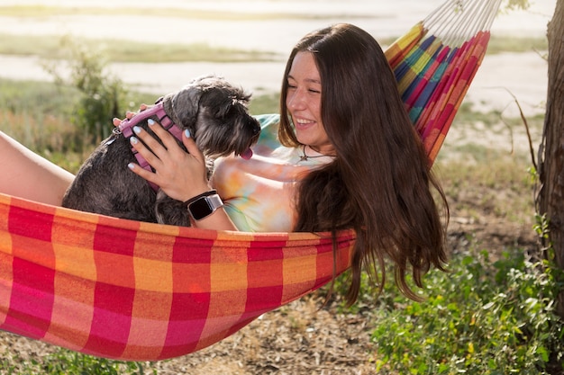 Girl outdoors, lies in a hammock and holds a miniature schnauzer dog in her arms, emotions, concept