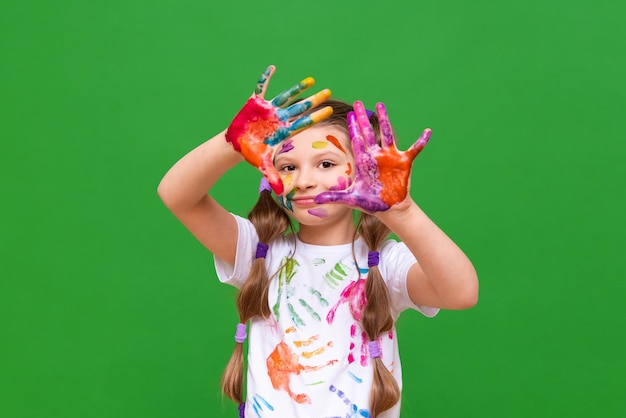 A girl in paint a child has stained her hands and face in paint and is happy A little girl with stained hands in paint on an isolated background