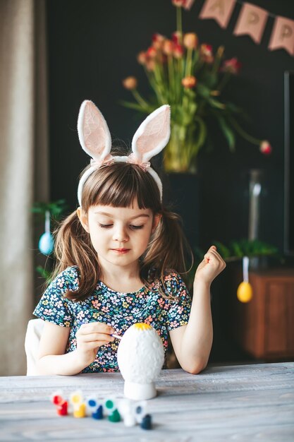 Girl painting Easter egg at home