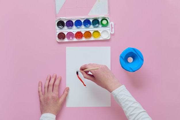 Girl painting on paper sheet with watercolors