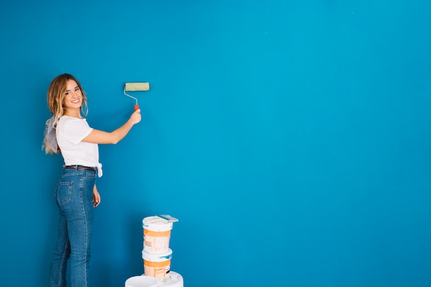 Girl painting wall with roll