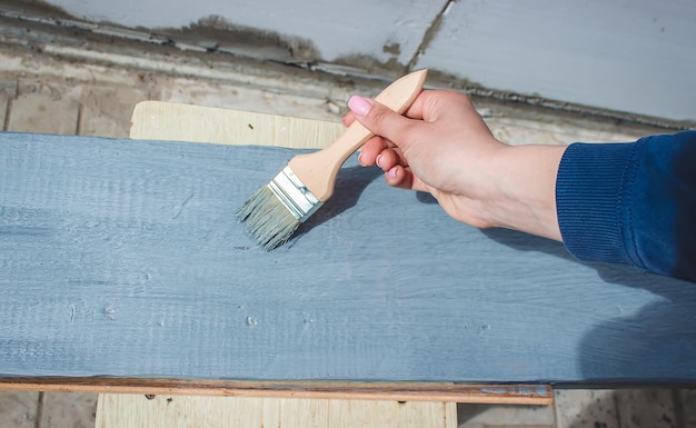 Girl paints a board with a brush Paint with gray paint