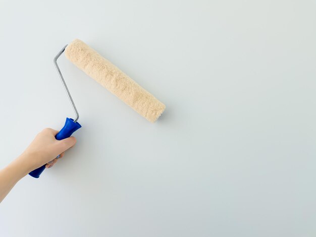 girl paints the wall with white paint female hand with wall paint roller close up with copy space