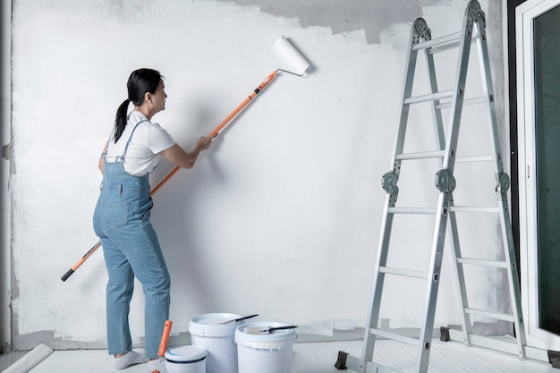 Girl paints a white wall with a roller