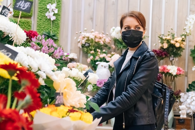 Girl during pandemic illness chooses a gift in a flower shop. The concept of the holiday and the purchase of a bouquet during the coronavirus